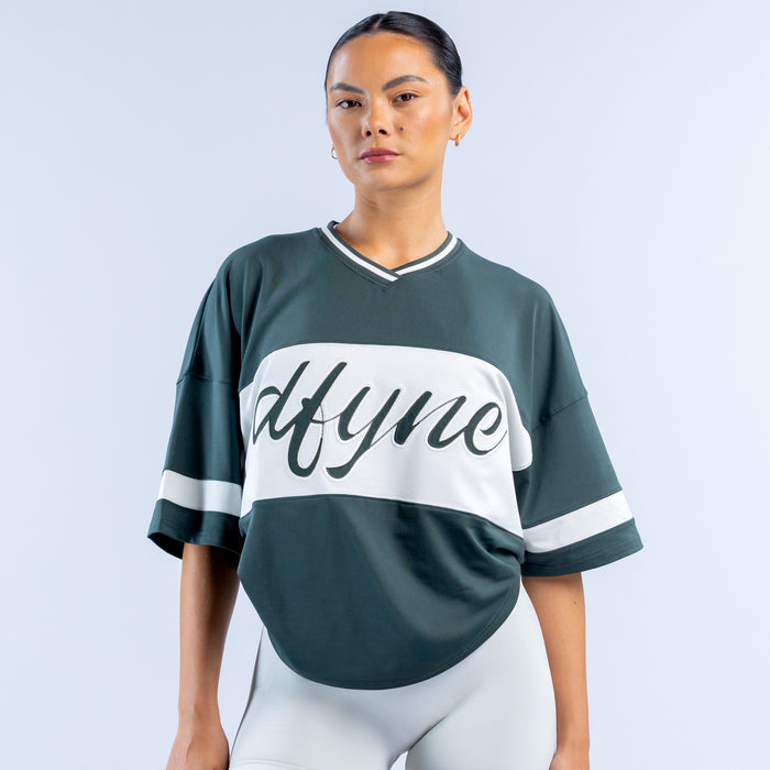 Dark green short sleeve top with white V-neck trim and large 'Mtyme' graphic