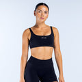 Black scoop-back sports bra with wide straps and DPYNE logo on front.