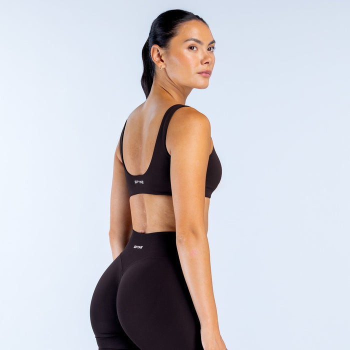 Black scoop back sports bra with racer back straps, DPNY logo, rear view