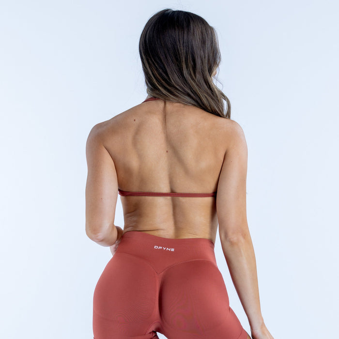 Back view of strappy bra in rust red with thin cross straps