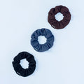 3-pack fabric scrunchies: dark brown, teal, and black with stitched DRYNE labels