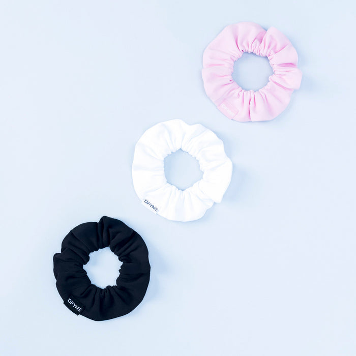Set of three satin scrunchies in pink, white, and black with gathered centers