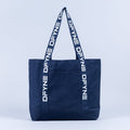 Navy canvas tote bag with vertical logo panel and navy webbing handles