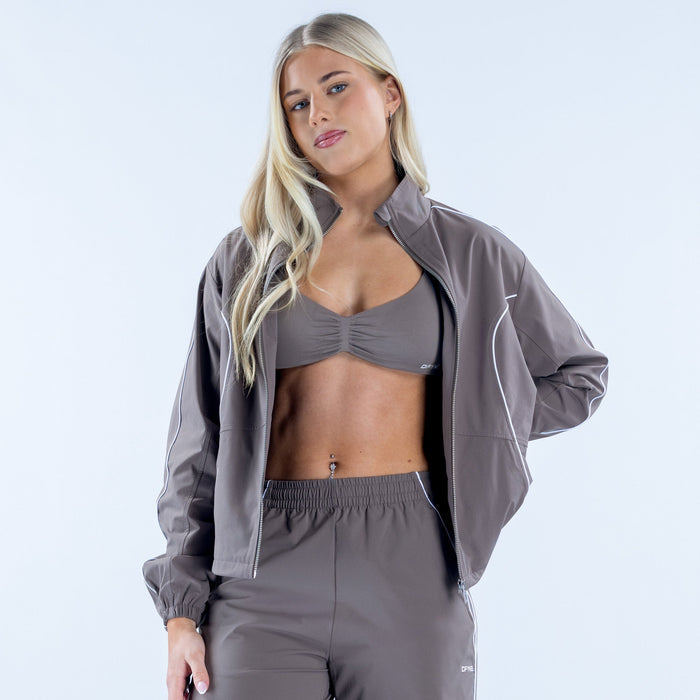 Women's gray track jacket worn over sports bra, full-zip with white piping