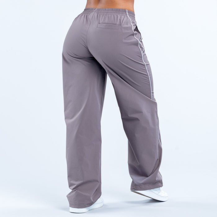 Dark gray track pants with white side piping, elastic waist and relaxed fit