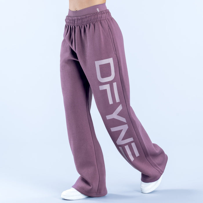Purple wide-leg jogger pants with elastic waistband and large vertical logo on leg