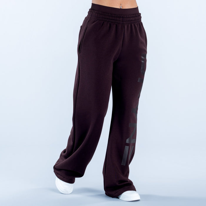 Dark maroon wide-leg jogger pants with elastic waistband and large side logo graphic